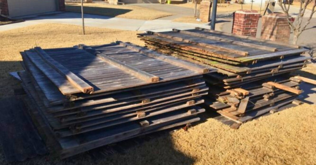 Stacked wooden fence panels on a lawn in Oklahoma City ready for junk removal.
